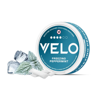 Ένα στρογγυλό μπλε και λευκό κουτί VELO Freezing Peppermint εμφανίζεται με παγάκια και φύλλα μέντας, τονίζοντας την έντονη γεύση μενθόλης. Η συσκευασία περιλαμβάνει ελληνικό και αγγλικό κείμενο καθώς και το σύμβολο προειδοποίησης ηλικίας "18+".