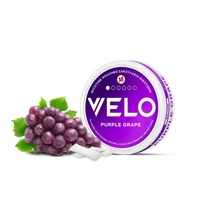 Ένα στρογγυλό δοχείο VELO Purple Grape βρίσκεται δίπλα σε φρέσκα σταφύλια και δύο λευκά σακουλάκια, προβάλλοντας τα φυτικά συστατικά του σε καθαρό λευκό φόντο.