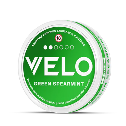 Ένα στρογγυλό δοχείο VELO Green Spearmint περιέχει σακουλάκια νικοτίνης, διαθέτει προειδοποίηση 18+ στο καπάκι και εμφανίζει αγγλικό και ελληνικό κείμενο στην ετικέτα.