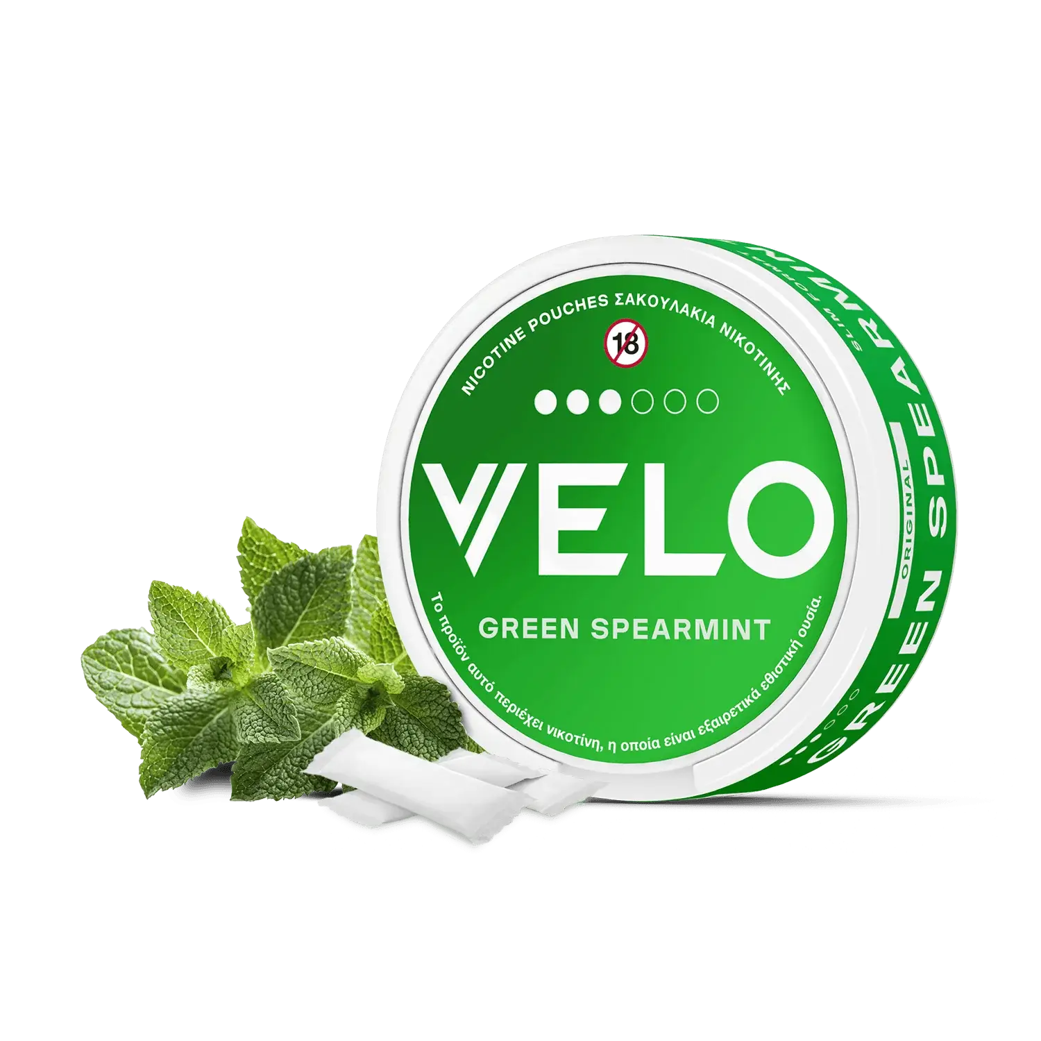 Ένα στρογγυλό πράσινο κουτί με την ένδειξη "VELO Green Spearmint" διαθέτει λευκό κείμενο, φύλλα μέντας και ένα σύμβολο "18+" στο καπάκι, επισημαίνοντας ότι πρόκειται για ένα σακουλάκι νικοτίνης μόνο για ενήλικες με φυτική βάση.