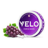 Ένα στρογγυλό δοχείο VELO Purple Grape βρίσκεται δίπλα σε ένα μικρό μάτσο σταφύλια και πράσινα φύλλα, με δύο λευκά φυτικά σακουλάκια νικοτίνης τοποθετημένα μπροστά.
