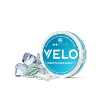 Ένα στρογγυλό δοχείο VELO Smooth Peppermint με μπλε και άσπρη ετικέτα βρίσκεται δίπλα σε φύλλα μέντας και παγάκια, τονίζοντας τη δροσερή, φρέσκια γεύση των μίνι σακουλιών που είναι φτιαγμένα από φυτικά συστατικά.