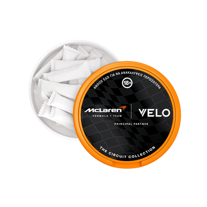 Ένα μεταλλικό κουτί με την ένδειξη «Velo Circuit Collection Limited» της VELO περιέχει αρκετές λευκές, μαξιλαροειδείς συσκευασίες Slim Pouches. Στο καπάκι εμφανίζεται το λογότυπο σε μαύρο και πορτοκαλί χρώμα, εμπνευσμένο από τη McLaren Racing, καθώς και κείμενο στα ελληνικά που υποδηλώνει περιορισμό ηλικίας 18+.