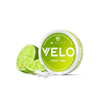 Ένα στρογγυλό δοχείο VELO Tangy Lime βρίσκεται δίπλα σε δύο μισά λάιμ, με λευκά φυτικά σακουλάκια νικοτίνης μπροστά, όλα σε λευκό φόντο.