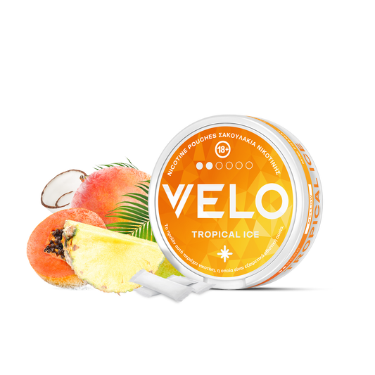 Ένα στρογγυλό κουτί VELO Tropical Ice βρίσκεται δίπλα σε φέτες ανανά, ροδάκινου και καρύδας, με δύο λευκά σακουλάκια νικοτίνης μπροστά. Το πορτοκαλί και λευκό κουτί διαθέτει έντονο κείμενο και σχέδιο εμπνευσμένο από γεύσεις τροπικών φρούτων.